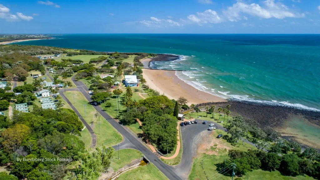 Aerial view of Bargara Beach in the Bundaberg Region, Queensland, showing golden sand, turquoise water, and the coastal parklands along the Coral Coast.