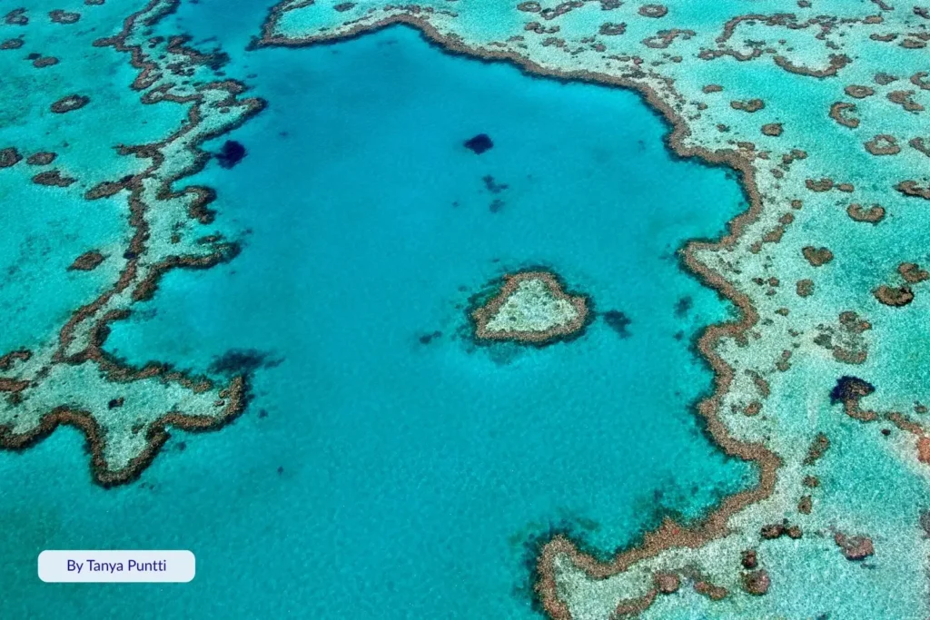 Scenic aerial view of Heart Reef, Whitsundays, Queensland, showing the heart-shaped coral lagoon within the Great Barrier Reefβs vivid blue waters.