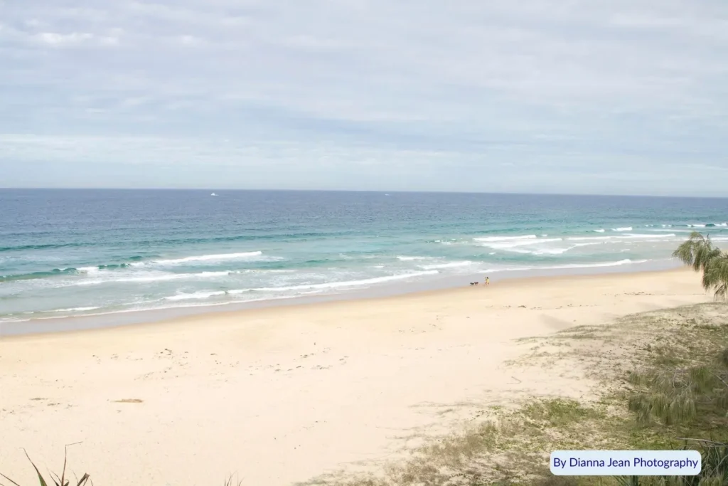 Wide sandy shoreline at Point Cartwright Beach, Sunshine Coast, Queensland β calm waves rolling onto golden sand under soft cloudy skies.