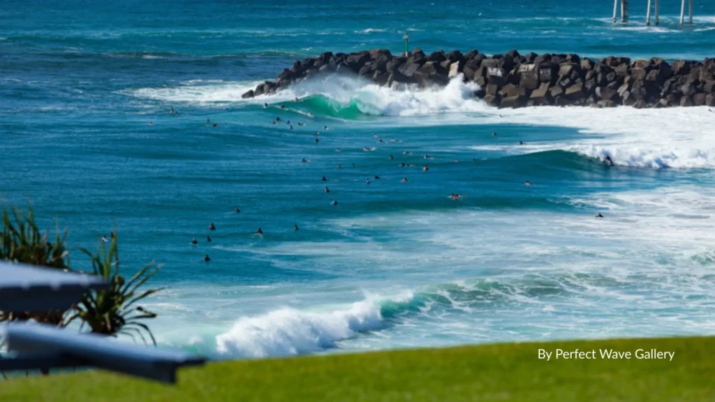 Surfers riding waves near the rock groyne at Duranbah Beach